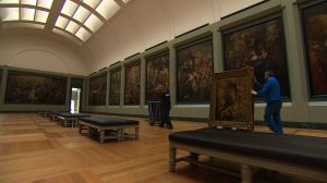 Picture hangers arrange the artworks in one of the Louvre's galleries